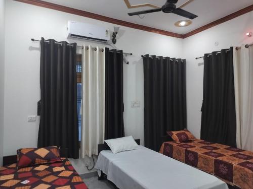 FaizābādHari Om Homestay的一间卧室设有两张床和黑色窗帘