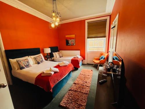 布由德利horn and trumpet的一间卧室设有两张床和橙色的墙壁