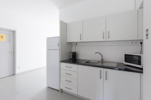 波尔图Smile4Porto Guest House的白色的厨房配有水槽和微波炉