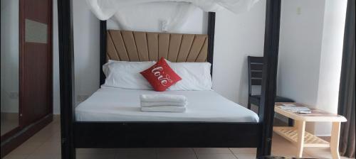 蒙巴萨SEBULENI LUXURY HOMESTAY - WALK TO NYALI BEACH Mombasa的一张黑色和白色的床,上面有红色枕头