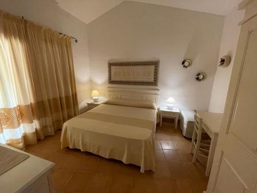 奇亚Delizioso villino Chia Sud Sardegna的一间卧室配有一张床、两张桌子和两盏灯。