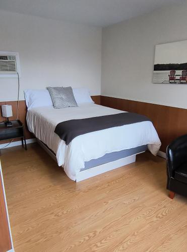 CabanoMotel Cabano-Relais的一间卧室配有一张大床和一把椅子