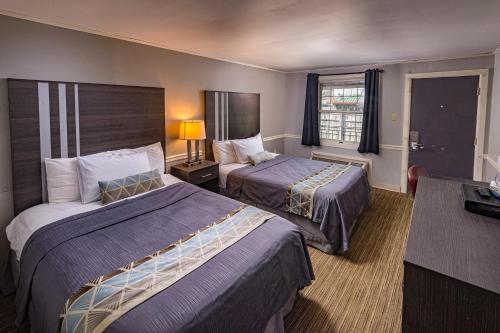 赫尔希Sunrise Inn Hershey的酒店客房设有两张床和一张桌子。