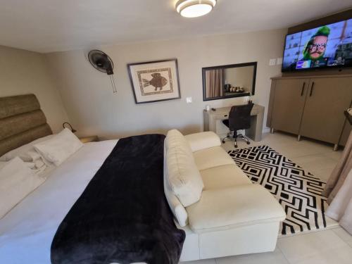 克鲁格斯多普Weston Guest House Krugersdorp的卧室配有白色的床、沙发和电视。