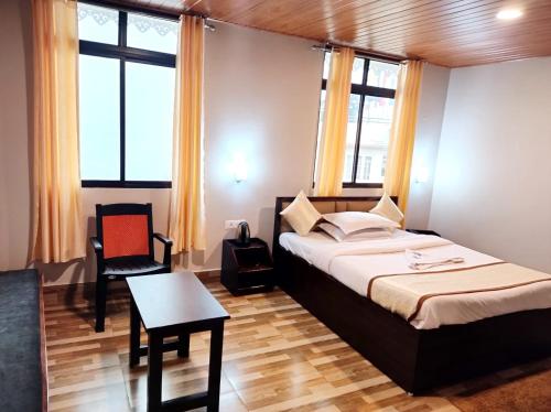 甘托克Hotel Sonar Tori的一间卧室配有一张床、一张桌子和一些窗户