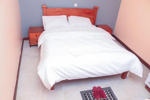 MeruTamwe ltd Airbnb &studios的卧室配有一张床铺,地板上放着两双红色鞋
