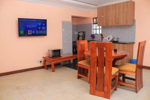 MeruTamwe ltd Airbnb &studios的厨房配有桌子,墙上配有电视。