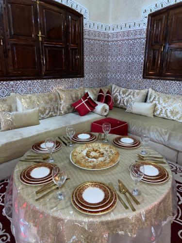 马拉喀什Riad malak的客厅配有带盘子和酒杯的桌子