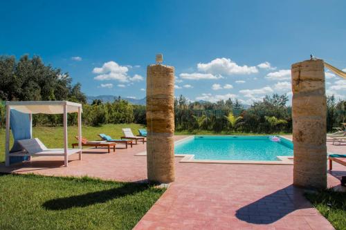 帕尔蒂尼科Villa con piscina Casale di Giò nel Golfo di Castellammare的后院设有游泳池和两个石柱
