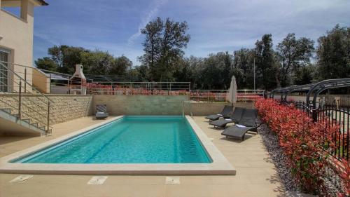 班约勒Ferienhaus mit Privatpool für 10 Personen ca 200 qm in Banjole, Istrien Istrische Riviera - b54844的一座带躺椅和躺椅的游泳池位于一座大楼旁