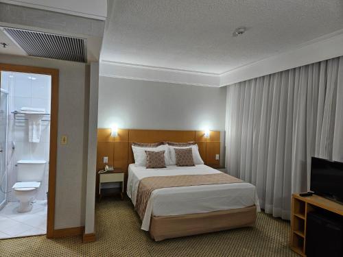 瓜鲁柳斯Flat Hotel Slaviero Guarulhos的酒店客房,配有床和电视