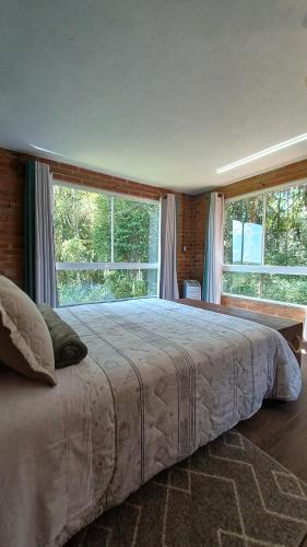 南卡希亚斯Casa aconchegante em meio a natureza的一间卧室设有一张大床和两个窗户