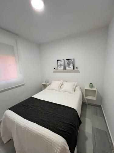 卡马斯Apartamento Jardín de Atalaya的白色卧室配有一张带黑色毯子的床
