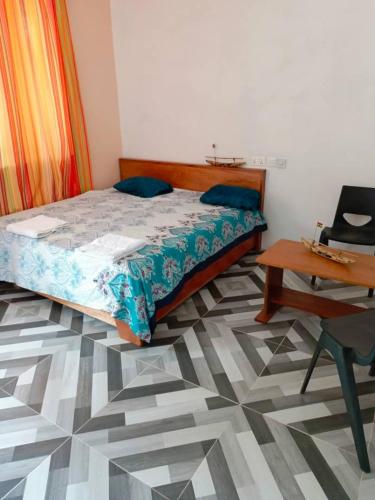 BusuaPalm Grove lodge的一间卧室配有一张床、一张桌子和一张书桌