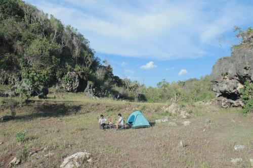 NgandongWisata Alam Lestari Gunung Semar的三人坐在帐篷旁边的田野里