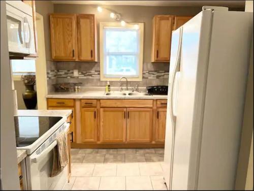 堪萨斯城The Woodland Villa的厨房配有木制橱柜和白色冰箱。