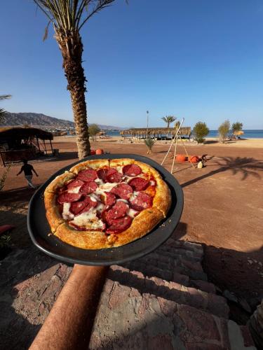 NuweibaSukoon Camp的坐在海滩旁桌子上的胡椒粉比萨饼
