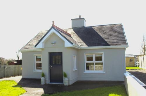 诺克Heather Cottage and Shepherds Hut的一间白色的小房子,设有蓝色的门