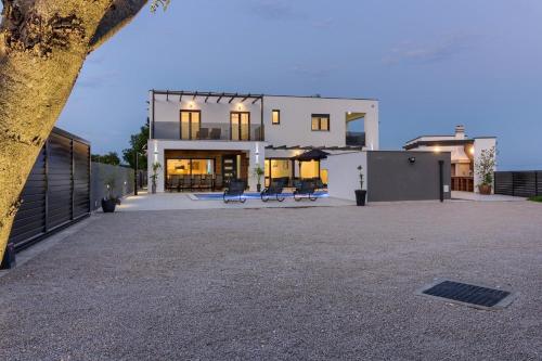 罗波里卡Ferienhaus mit Privatpool für 14 Personen ca 280 qm in Loborika, Istrien Südküste von Istrien的前面有两长椅的大白色房子