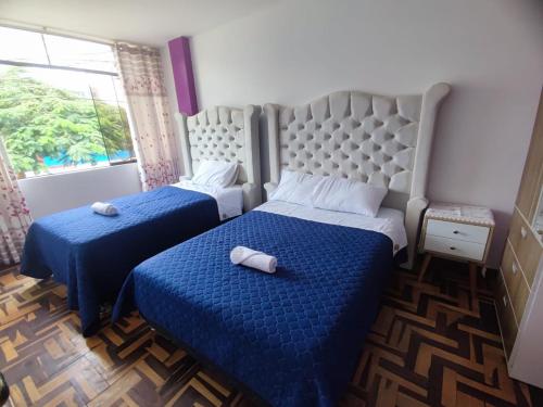 利马SUMAQ PUÑUY HOSTEL - LIMA AIRPORT的一间卧室设有两张带蓝色床单的床和窗户。