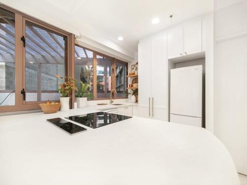 奥克兰Charming 1 Bedroom Apartment in Auckland的白色的厨房,配有玻璃台面