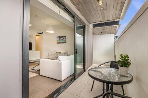 奥克兰Bright & modern Auckland CBD apartment的阳台配有桌子和沙发。