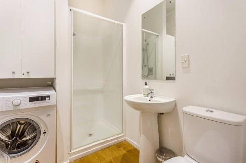 奥克兰Cosy Queen St 1-BR apartment的白色的浴室设有洗衣机和水槽。