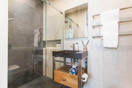 奥克兰Luxury meets location - 2RB in Ponsonby的一间带玻璃淋浴和水槽的浴室
