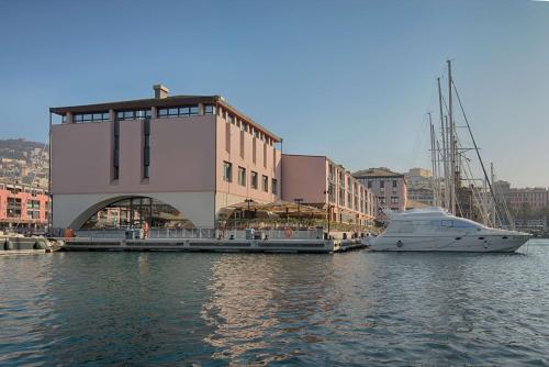 热那亚热那亚码头NH典藏酒店的船停靠在水面上的建筑物旁边