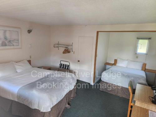 坎贝尔河Campbell River Lodge的一间卧室设有两张床、一张桌子和一个窗口