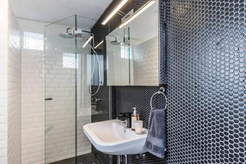 悉尼Modern Sydney Surry Hills Century Cottage的一间带水槽和玻璃淋浴的浴室