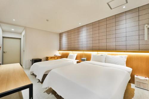 庆州Ciel mini hotel的配有白色床单的酒店客房内的两张床