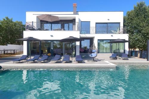 罗波里卡Ferienhaus mit Privatpool für 10 Personen ca 300 qm in Loborika, Istrien Südküste von Istrien的一座房子,设有一座带椅子和遮阳伞的游泳池
