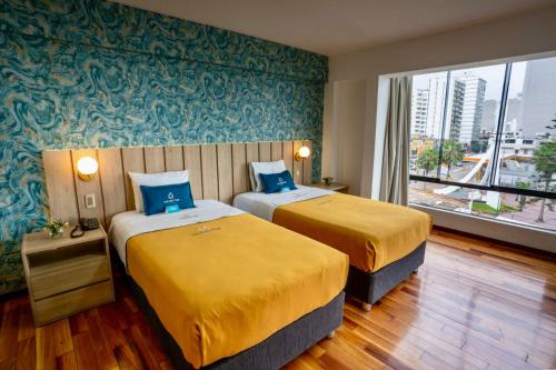 利马Golden Mar Hotel的酒店客房设有两张床和大窗户。