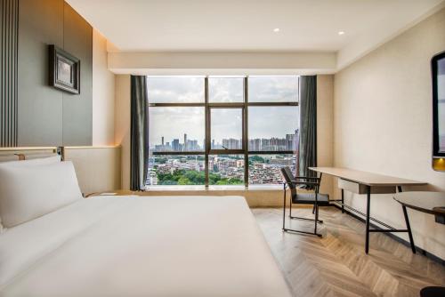 广州广州珠江太古仓亚朵S酒店的一间卧室配有一张床、一张书桌和一个窗户。
