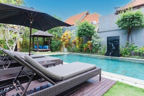 沙努尔禅宗别墅酒店的游泳池旁的游泳池配有椅子和遮阳伞