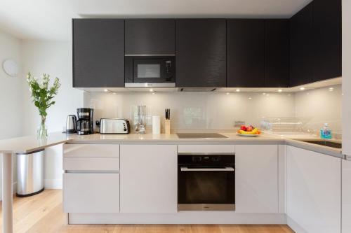 伦敦Central Fitzrovia - 1BR - CityApartmentStay的厨房配有白色家电和黑色橱柜