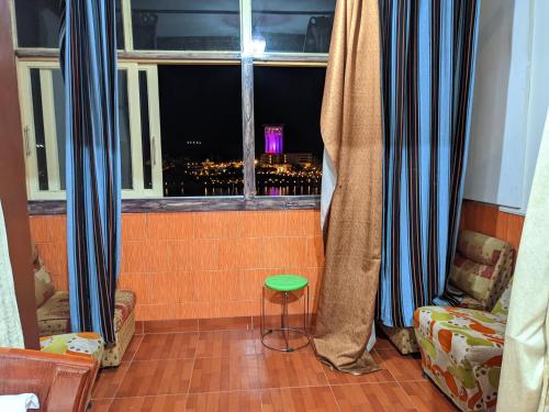 阿斯旺TOP HOTEL的客房设有带蓝色窗帘和凳子的窗户。