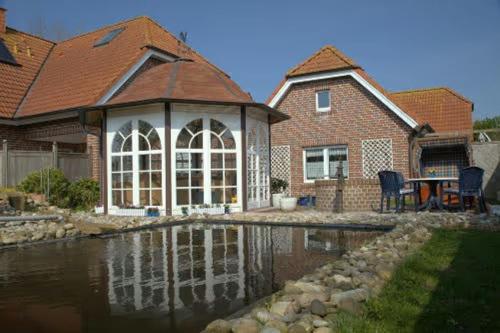 博尔库姆Ferienhaus Inselkate的房屋前有池塘的房子