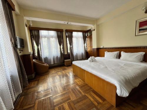 甘托克Yesheyzz的卧室配有一张带白色床单和木地板的大床。