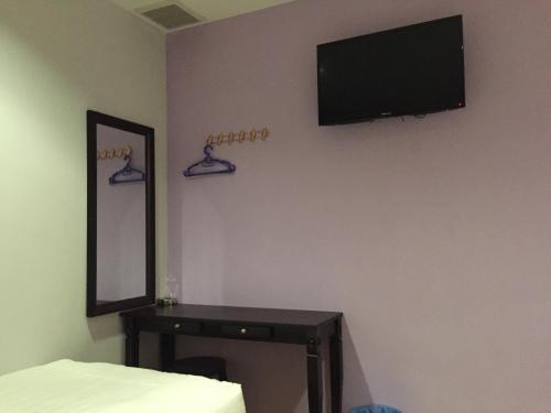 甘榜巴鲁泰斯樱花经济型酒店 的卧室设有壁挂式电视和桌子。