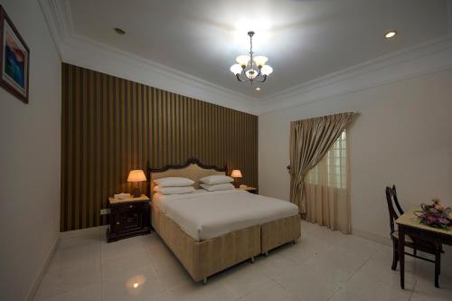 乌姆盖万Royal Residence Hotel Apartments的一间卧室配有一张床、一张桌子和一个吊灯。