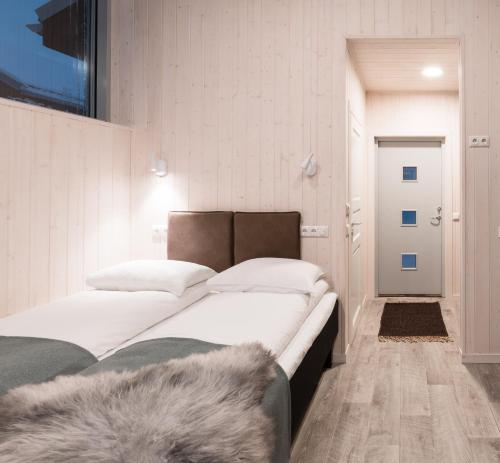 特罗姆瑟特罗姆瑟小屋露营地的一间卧室配有一张带白色床单和地毯的床。