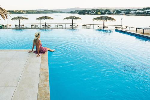 维拉港伊利利奇岛Spa度假酒店的坐在游泳池边缘的女人