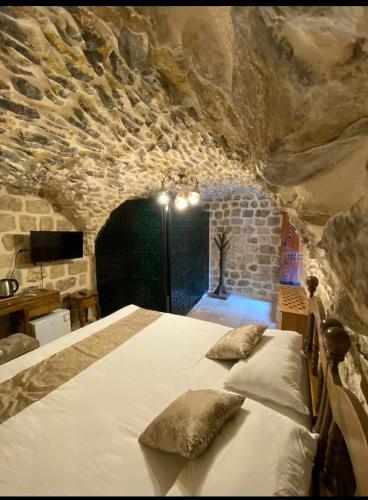 马尔丁Old City Tourism的卧室配有一张石墙内的大床