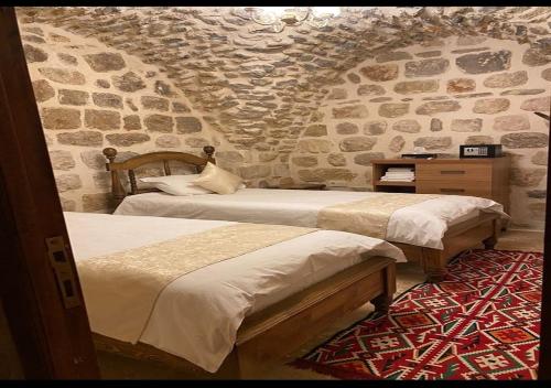 马尔丁Old City Tourism的一间卧室设有两张床和石墙