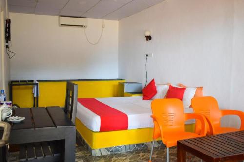 亭可马里金海滩别墅 的配有橙色椅子和桌子的床的房间