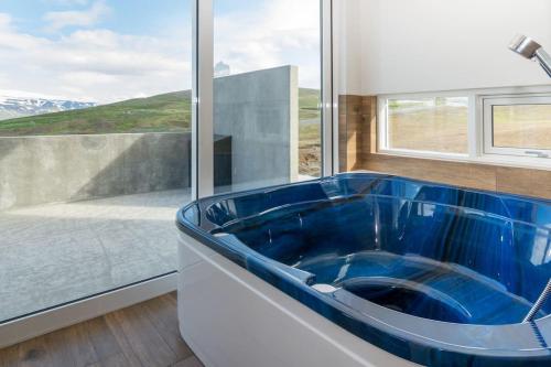 阿克雷里Private cottage, elegance & amazing view的窗户前带蓝色浴缸的浴室