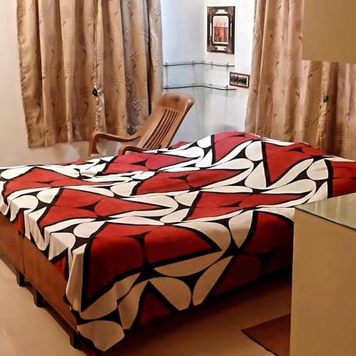 特里凡得琅Parthasarathy的一张带红白毯子和椅子的床