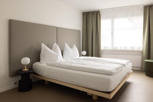 苏黎世EMA House Serviced Apartments Aussersihl的一间卧室配有一张带白色床单的床和一扇窗户。